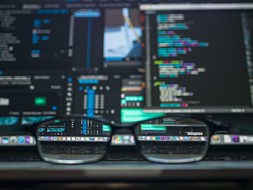 black rimmed glasses in front out of focus code computer screen