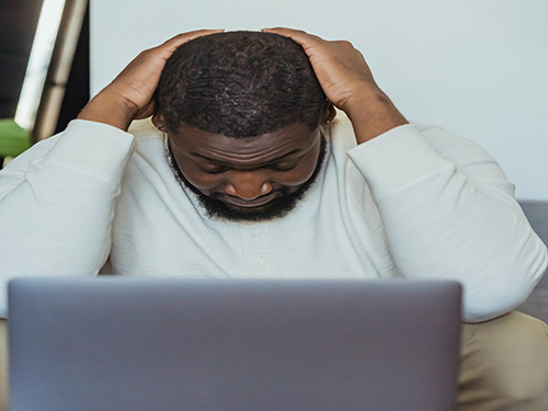 man hangs head in front of computer